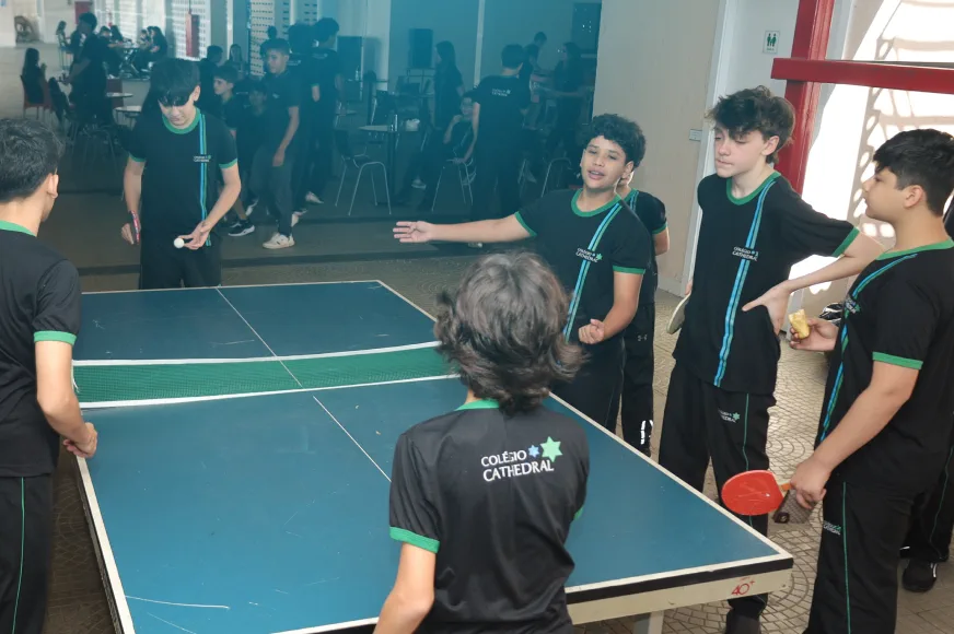Estudantes jogando tênis de mesa na área de convivência